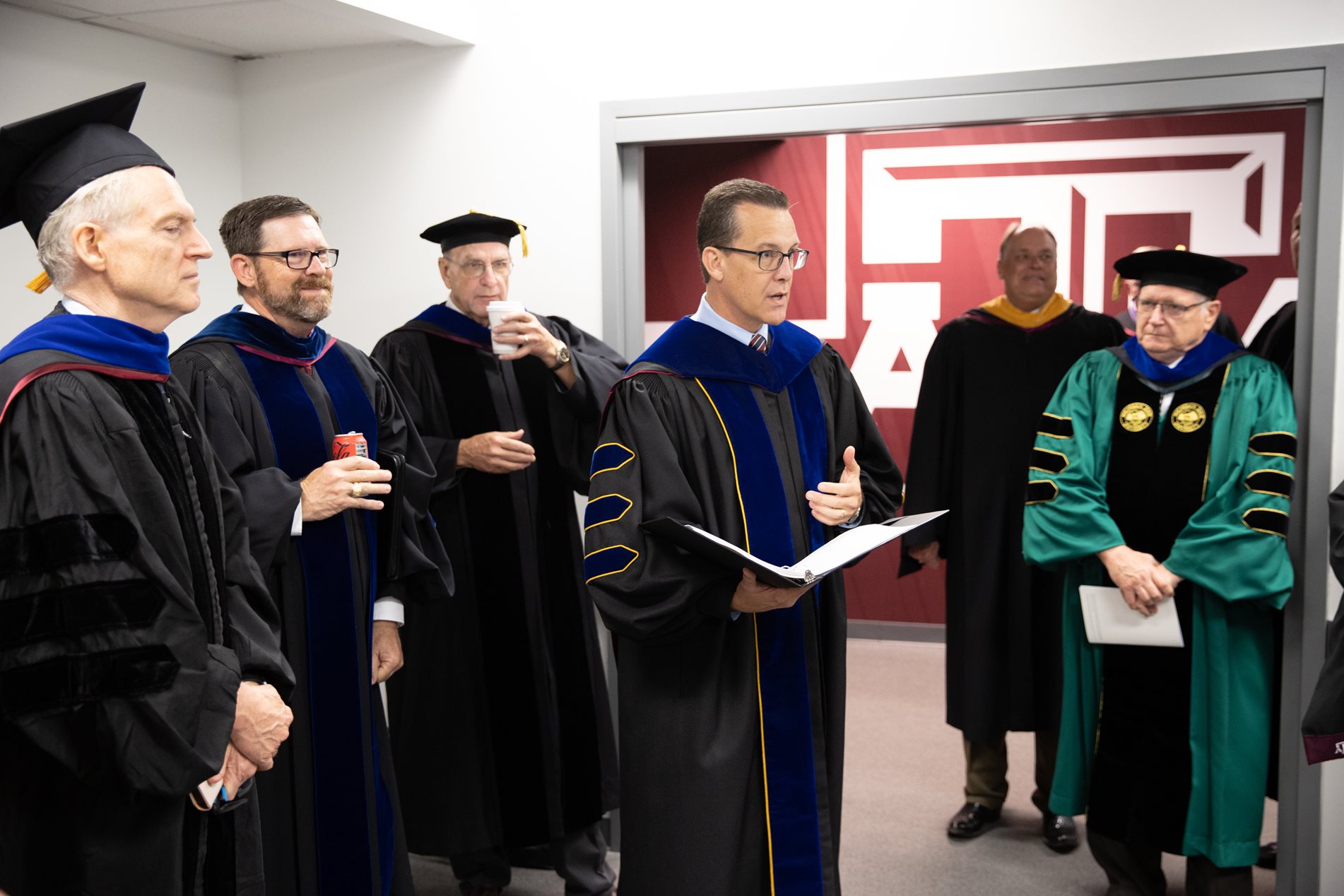 Group of male faculty and staff before the ceremony in regalia
